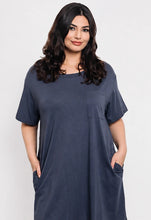 Woman wearing a blue dress with pockets on a white background