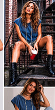 Woman in blue top and black boots sitting on a staircase holding a red cup.